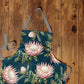 Proteas on Teal Medium Length Apron By Mark Van Vuuren